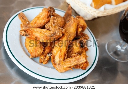 Picture of dish of tasty fried chicken wings served at plate on table