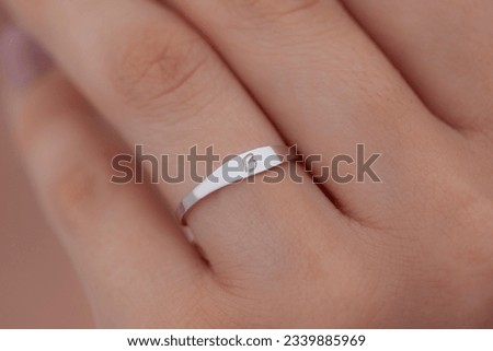 A silver ring in the hand of a well-groomed lady. Product image that can be used in e-commerce, social media, online sales. Jewel photo with women's jewelry concept.