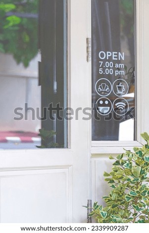White wooden entrance door of vintage coffee shop with information service icon signs on glass window in vertical frame