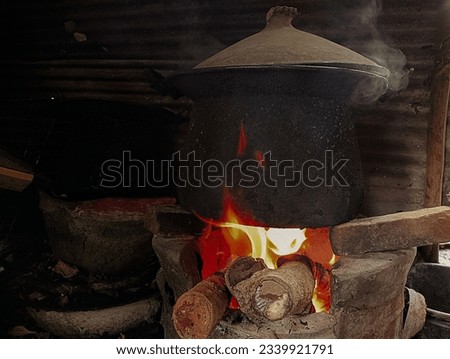 This picture represents the making of a fire to set up a pot to make boiled rice to make merit at a temple in Thailand.