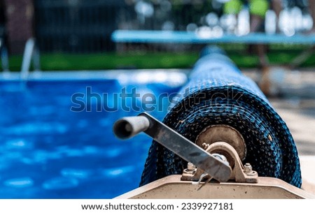 Manual real for a retractable floating pool cover to keep out leaves and keep in heat.  Royalty-Free Stock Photo #2339927181