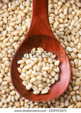 Cleaned pine nuts. Pine nut kernels lie in wooden spoon. Top view of nuts close-up. Advertising photography for marketplaces or online stores.