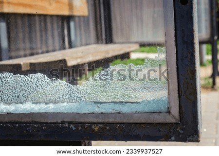 Vandalised Broken bus stop glass in the city.This is a manifestation of wild vandalism.Dangerous,crashed tempered glass pieces on ground. Royalty-Free Stock Photo #2339937527