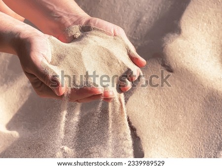 Handful of sand in the women's hands, selective focus. The sand pouring from female hands. Royalty-Free Stock Photo #2339989529