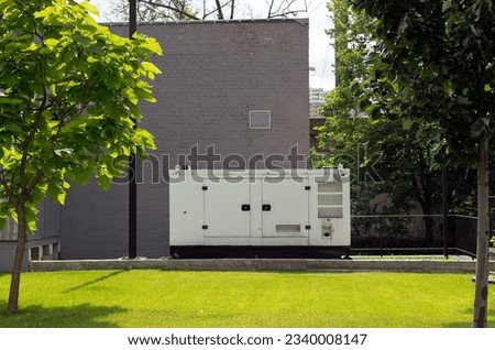 auxiliary diesel generator for emergency power supply. Industrial generator connected to the control panel by a cable wire. Backup power supply of the generator Royalty-Free Stock Photo #2340008147