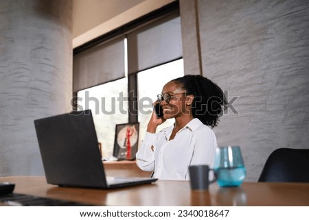 Black businesswoman working on laptop. Portrait of beautiful businesswoman in the office. Woman taking to the phone.	