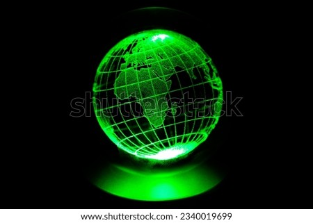 World map model engraved with a laser inside a glass globe. World map with green neon light on isolated black background. Asian and African continents are in the foreground. Clean world concept.
