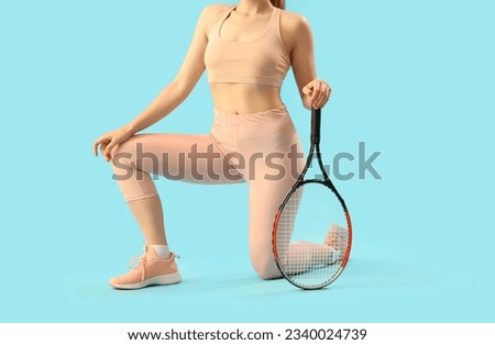 Young woman in sportswear and with tennis racket on light blue background