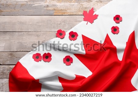 Flag of Canada and poppy flowers on wooden background. Remembrance Day
