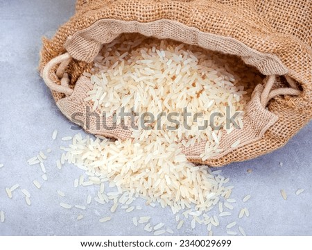 white rice pouring from a burlap sack on grey