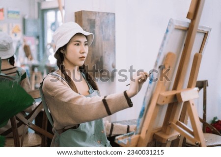 Young female artist painting on canvas in the home studio, fine arts and creativity concept.