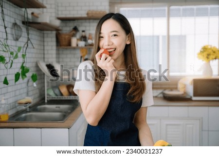 Woman is cooking in home kitchen. Female hands cut bell pepper, vegetables, greens, tomatoes on table on wooden boards. Healthy food, salad or vegetarian food.