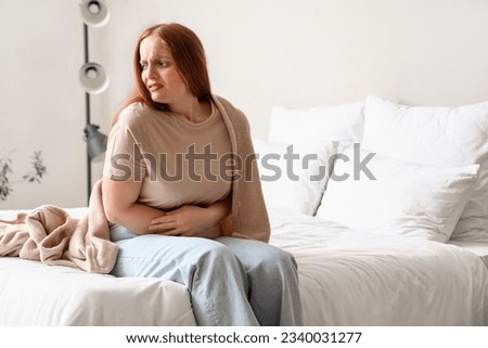 Young woman having menstrual cramps in bedroom Royalty-Free Stock Photo #2340031277