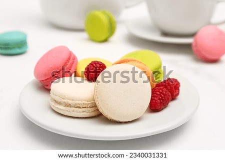 Plate with sweet macaroons and raspberries on white background Royalty-Free Stock Photo #2340031331