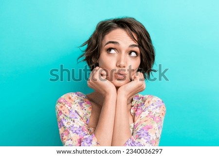 Photo of adorable minded girl pouted lips arms touch cheekbones look empty space isolated on teal color background