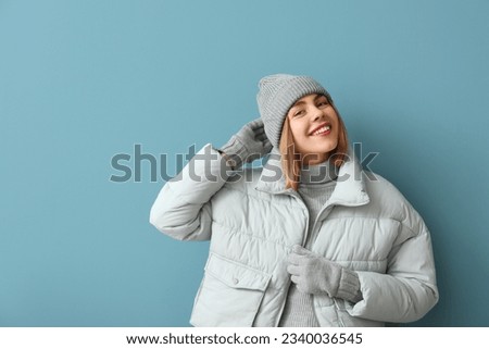 Frozen young woman in winter clothes on blue background Royalty-Free Stock Photo #2340036545