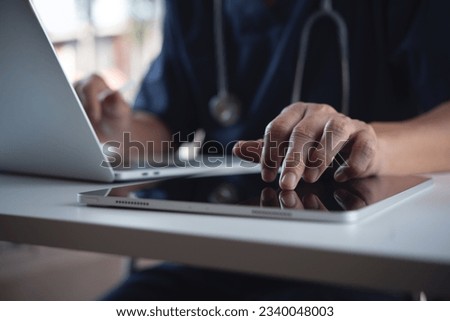 Close up of doctor, surgeon using digital tablet and laptop computer during working in doctor's office, healthcare and medicine, electronic health record system concept Royalty-Free Stock Photo #2340048003