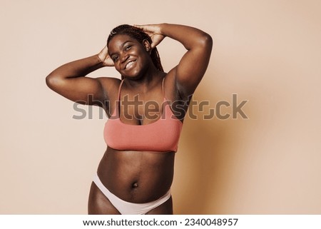 Beautiful smiling happy african woman with hands behind her head standing over isolated brown background