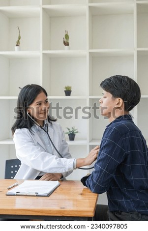 Asian man patient are checked up his health while a woman doctor use a stethoscope to hear heart rate of him Royalty-Free Stock Photo #2340097805