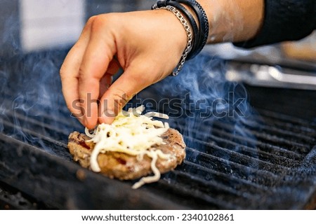 man hand cooking cheeseburger on grill