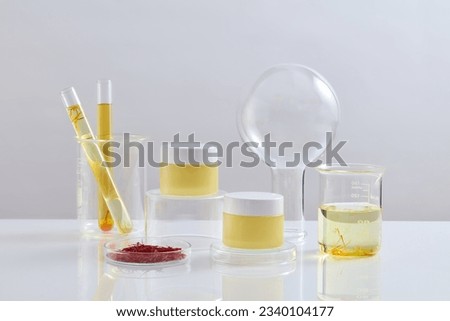 Two yellow jars placed on transparent podiums. A petri dish of saffron, test tubes and a beaker of fluid are displayed. Branding mockup with empty label