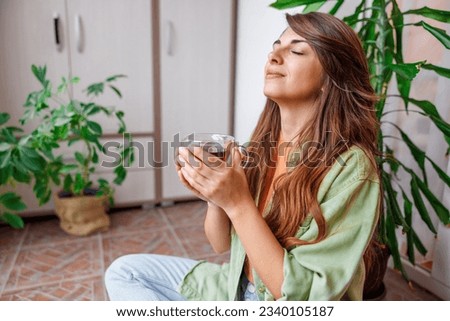 Beautiful young woman relaxing at home sitting at her balcony drinking hot tea Royalty-Free Stock Photo #2340105187