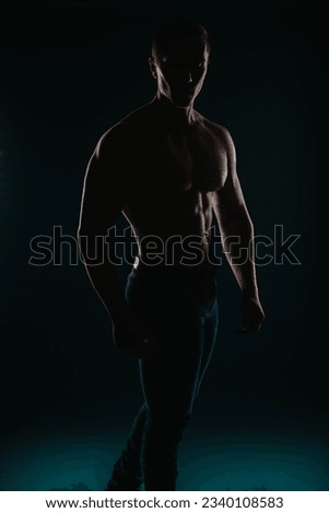 Well-built and charming man standing in front of a dark background and posing Royalty-Free Stock Photo #2340108583