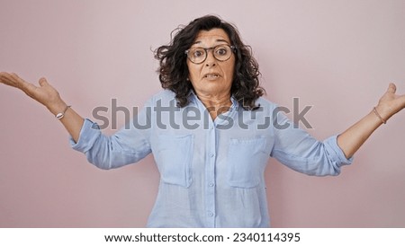 Middle age hispanic woman standing clueless over isolated pink background