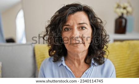 Middle age hispanic woman sitting on sofa with serious face at home Royalty-Free Stock Photo #2340114745