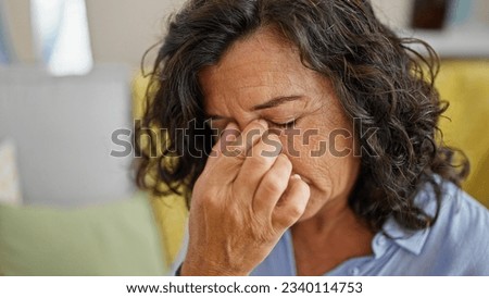 Middle age hispanic woman stressed sitting on sofa at home Royalty-Free Stock Photo #2340114753