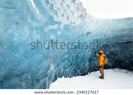 A traveler finds himself detained in an impressive landscape of ice inside the Vatnajokull National Park, in Iceland. The dazzling ice formations and intricate patterns reveal the magnificent beauty o Royalty-Free Stock Photo #2340127617