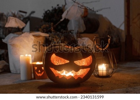 Spooky Jack o lantern, spiders, pumpkin and glowing candles in dark. Halloween porch and entrance decor. Scary halloween decorations outside of house. Trick or treat