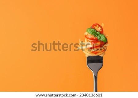 Tasty pasta with tomato sauce and basil on fork against orange background, space for text Royalty-Free Stock Photo #2340136601