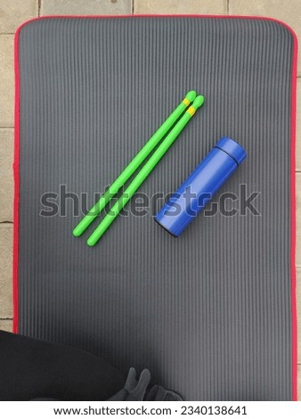 stick for exercise pound fit.  it is called ripstix.  above black mat.  completed with drinking bottles Royalty-Free Stock Photo #2340138641
