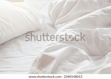 wrinkle messy blanket and white pillow in bedroom after waking up in the morning, from sleeping in a long night, details of duvet and blanket, an unmade bed in hotel bedroom with white blanket. Royalty-Free Stock Photo #2340148013
