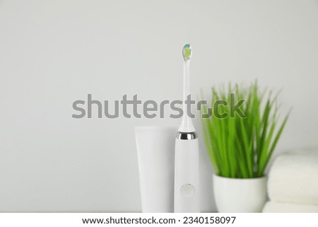 Electric toothbrush and tube with paste on light background
