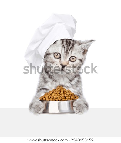 Cat wearing chef's hat holding bowl of dry food and looking above empty white banner. isolated on white background.