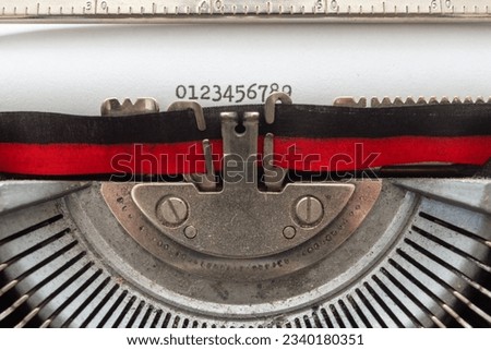 typing with an old typewriter. The numbers from 0 to 9, written on a white sheet of paper, with a two-tone, black and red ribbon, and the rest of the steel mechanisms of the typewriter.