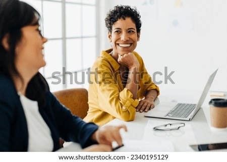 Happy business woman talking to her colleague in a boardroom. Group of business professionals having a team meeting. Creative business people planning a project in an office. Royalty-Free Stock Photo #2340195129