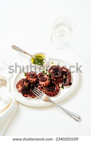 boiled octopus on a plate with green sauce. served with white wine