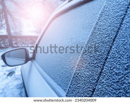 Window of the car covered with frost during winter morning and sun flare light reflecting