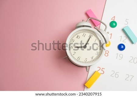 close up of calendar and alarm clock on the pink table background, planning for business meeting or travel planning concept