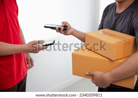 A man in a red t-shirt is delivering a package to a satisfied customer. Friendly staff, high quality delivery service. Royalty-Free Stock Photo #2340209811
