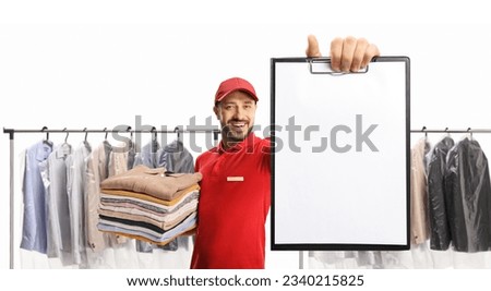 Laundry worker holding a pile of clothes and showing a blank paper document at the dry cleaners isolated on white background