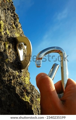 Hand attaching carabiner to a rock anchors