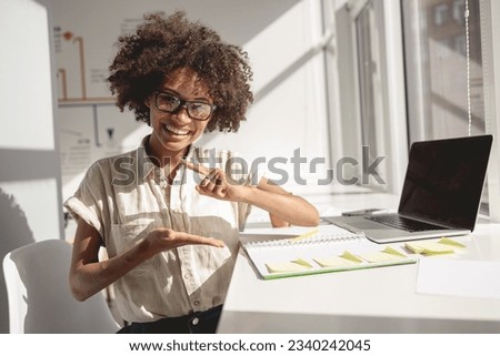 African American woman at the table and gesturing with her hands while sitting near window Royalty-Free Stock Photo #2340242045