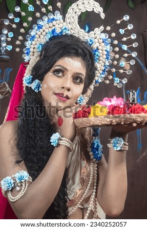 Close up portrait of an young and beautiful Indian Bengali brunette woman in red and white traditional sari and jewelry on the occasion of Durga Puja. Maa Durga agomoni shoot concept. Indian culture.