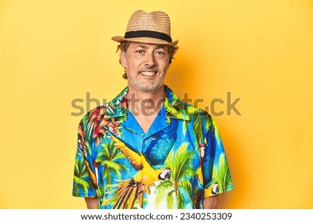 Cheerful middle-aged man in Hawaiian shirt emanating summer vibes on a yellow background Royalty-Free Stock Photo #2340253309