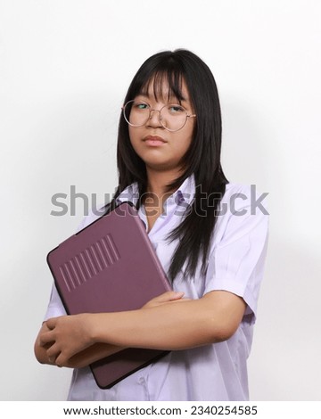 Portrait of a serious concentrated young student embracing her laptop on white color background