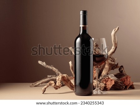 Bottle and glass of red wine with a composition of old wood. Minimalistic composition on a beige background for product branding, identity, and packaging. Copy space. Royalty-Free Stock Photo #2340255343
